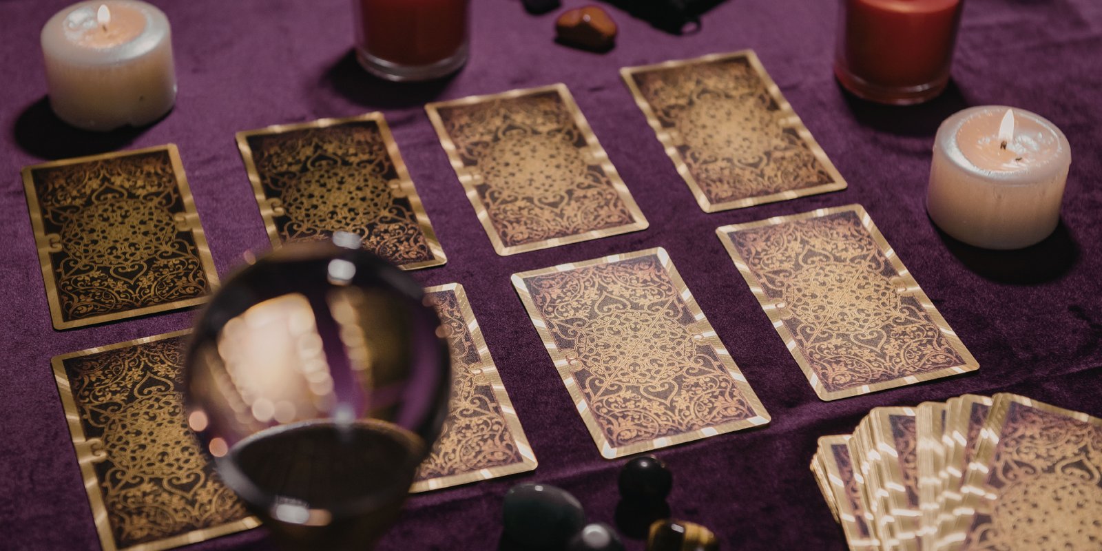 Tarot cards, candles and a crystal ball on purple cloth